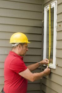 A window installation technician measuring for a window replacement