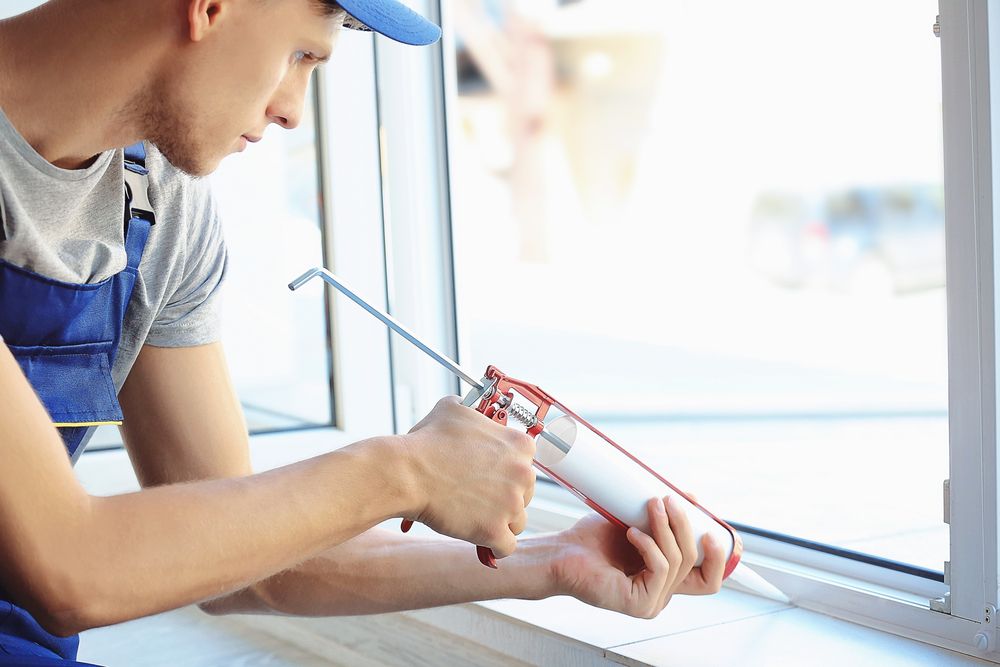 man installs window on a house