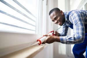 applying new caulk to window