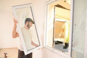 A man putting in replacement windows. Review eight replacement window warranty questions to ask your installer today.